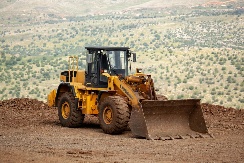 Yellow loader at construction site in Adıyaman, Türkiye against mountainous backdrop.